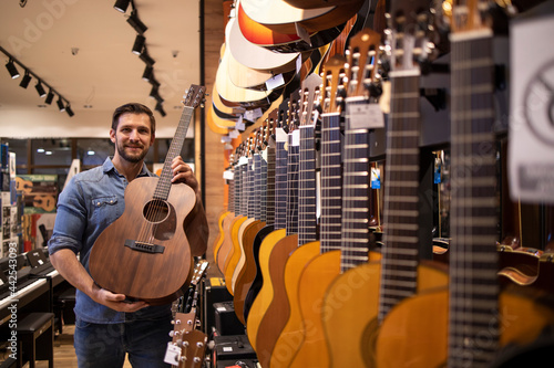 Guitar seller showing new model of guitar in music shop.