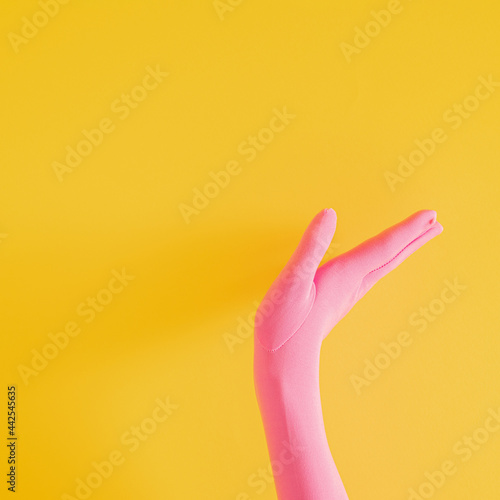 hands with pink glove on yellow sunny summer background. modern summer abstract art. mimalism