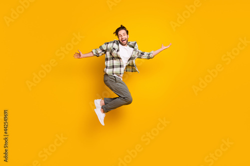 Full length photo of cheerful happy man jump up raise hands good mood smile isolated on yellow color background