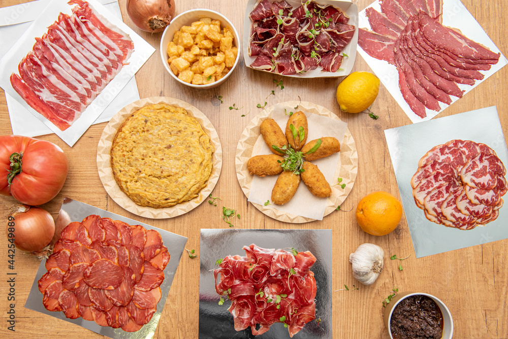 Set of typical Spanish dishes for tapas bar and popular cold cuts. Patatas bravas, tortilla potatoes, cod croquettes, sausage loin, acorn ham Set of typical Spanish dishes for tapas bar and popular cold cuts. Patatas bravas, tortilla potatoes, cod croquettes, sausage loin, acorn ham