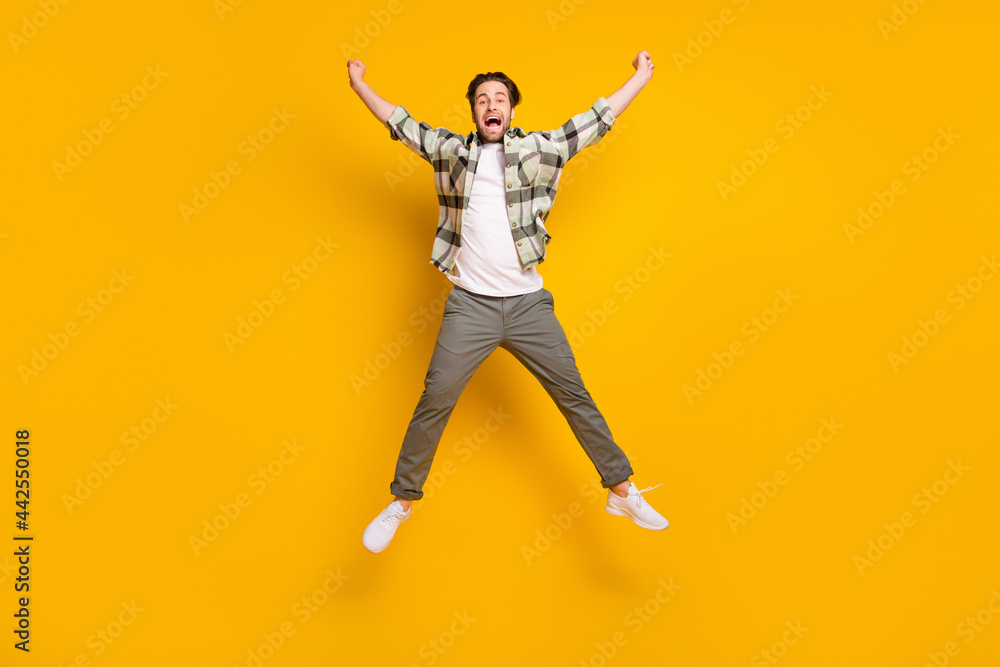 Full length photo of cheerful young active man jump up good mood smile isolated on yellow color background