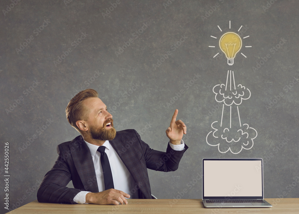 Happy inspired man in suit sitting at office desk with laptop computer ...