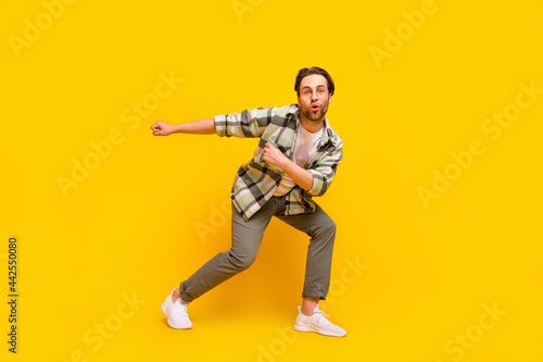 Full size photo of young excited man happy positive smile dance hip-hop music isolated over yellow color background