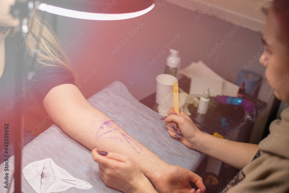 Close up temporary tattoo on arm of client which making worker. Preparation. Transfer the sketch to the body. Close up temporary tattoo on arm of client which making worker. Preparation. Transfer the sketch to the body.