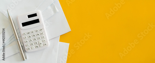 close up top view on calculator and open over group of invoice letter mail from  bank on yellow background for money and debt  management concept photo