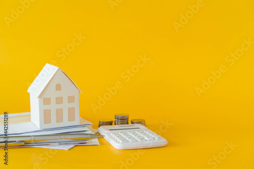close up of home model and calculator and invoice letter on yellow background with space for money management ,home loan and personal financial concept	