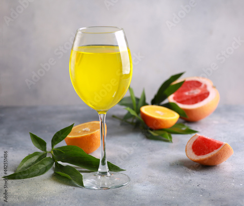 Summer. Drinks. Fruit tropical cocktail with orange, grapefruit in a transparent glass and a branch of greenery on a light gray background. Background image, copy space