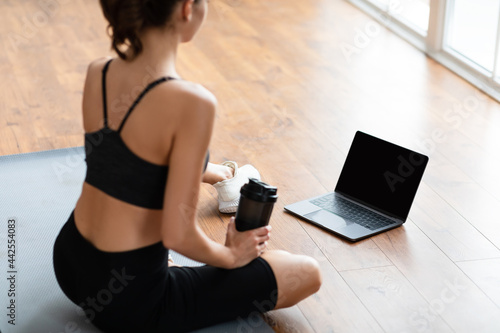 Young woman sitting on mat with pc