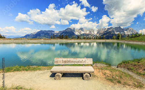 Famous wooden bench Lieblingsplatzl at the Astbergsee lake on the Astbergalm in Going at the Wilder Kaiser mountains