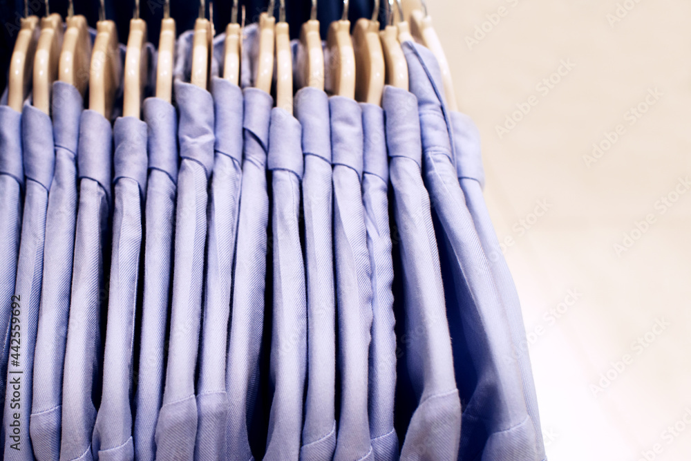 Cotton blue shirts on hangers in supermarket close up, selective soft focus