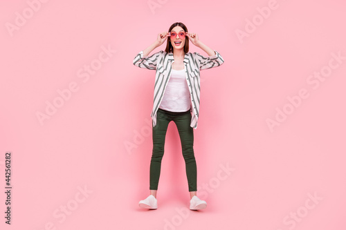 Full length photo of young excited girl happy positive smile have fun sunglass isolated over pastel color background © deagreez