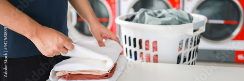Slika na platnu Man doing launder holding basket with dirty laundry of the washing machine in the public store