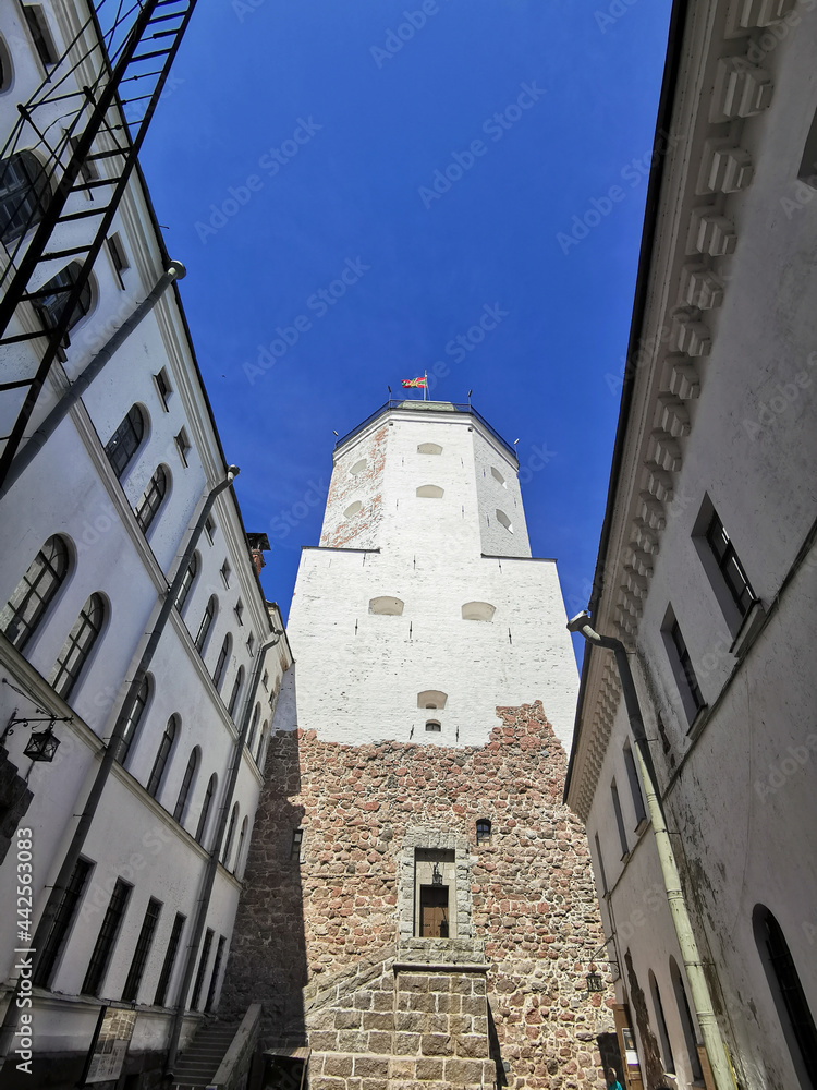 The courtyard of the Vyborg Castle and the entrance to the St. Olaf Tower in the city of Vyborg against the blue sky.
