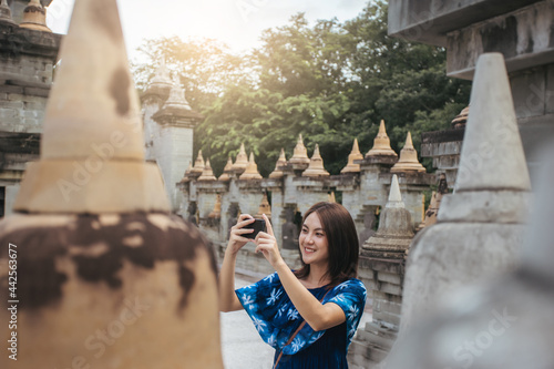 Traveler Asian woman happy smile use smartphone taking photo in attractions of ASia after recovered from pandemic coronavirus. Travel trip concept after pandemic COVID-19