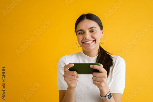Wallpaper Mural Young brunette woman playing online game on mobile phone Torontodigital.ca