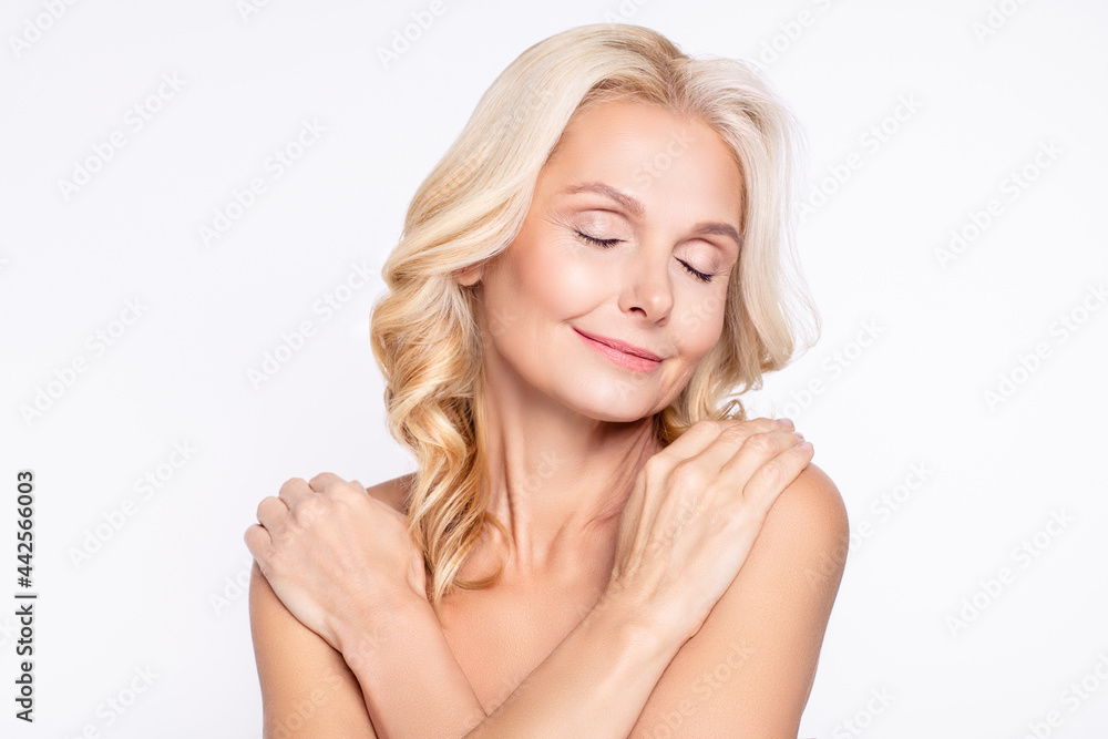Portrait of attractive dreamy healthy grey-haired woman hugging shoulders after shower gel peeling isolated over white color background Portrait of attractive dreamy healthy grey-haired woman hugging shoulders after shower gel peeling isolated over white color background