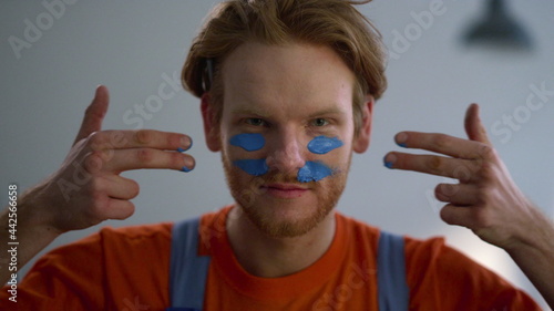 Fotografie Cheerful man putting war paint on face during house renovation in new home