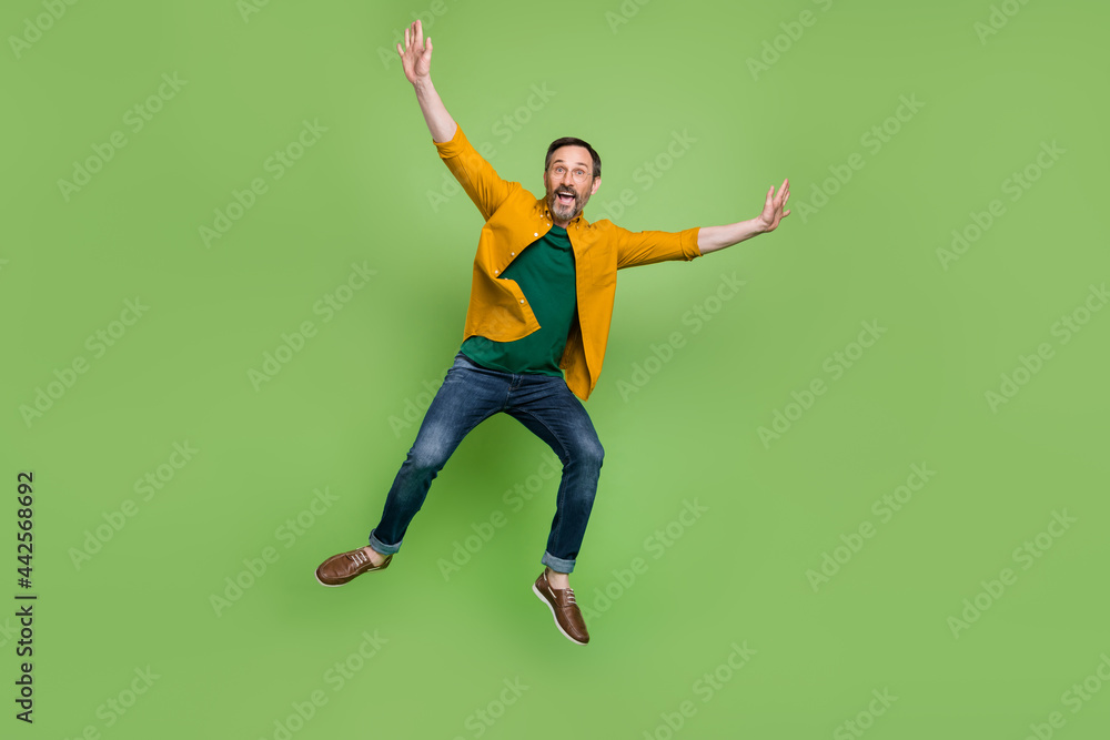 Full body photo of positive mature happy man jump up air raise hands enjoy isolated on green color background
