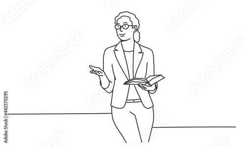 Female teacher gesturing with hand, holding book and talking.