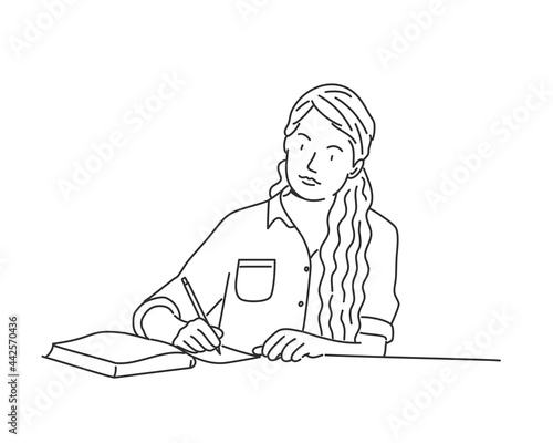 Cute woman with long hair writing a letter or doing homework at the table.