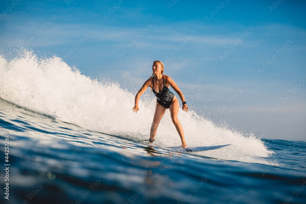 Surfer girl ride on wave at surfboard. Sporty woman in ocean surfing.