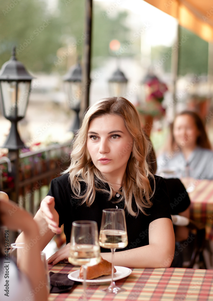 Women at cafe drinking white wine and talking. Communication and friendship concept. Women at cafe drinking white wine and talking. Communication and friendship concept.
