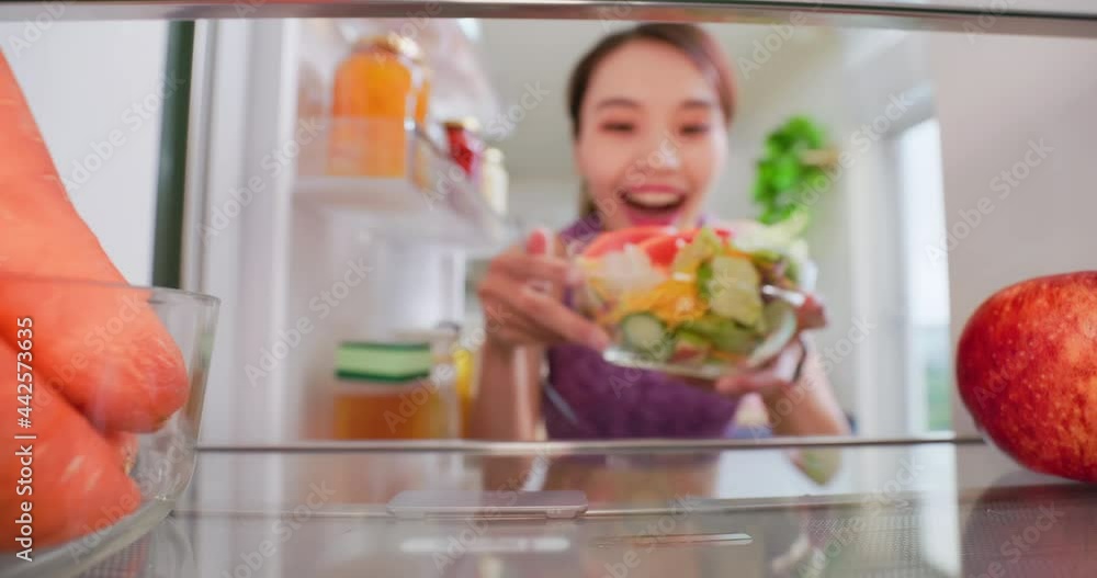 woman takes salad from refrigerator woman takes salad from refrigerator