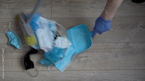 Covid-19 disposable ppe waste. A man sweeps up medical waste, used face masks and gloves. The concept of environmental pollution. Close-up. Top view. Faceless. 4K. photo