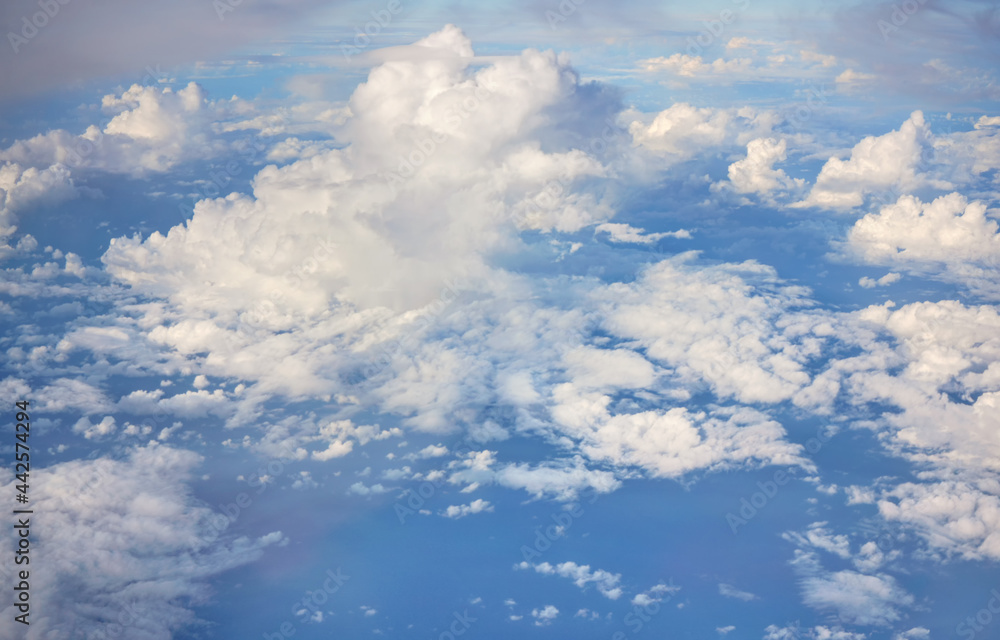 Fluffy sky clouds lit by afternoon sun, as seen from commercial airplane flying over Fluffy sky clouds lit by afternoon sun, as seen from commercial airplane flying over