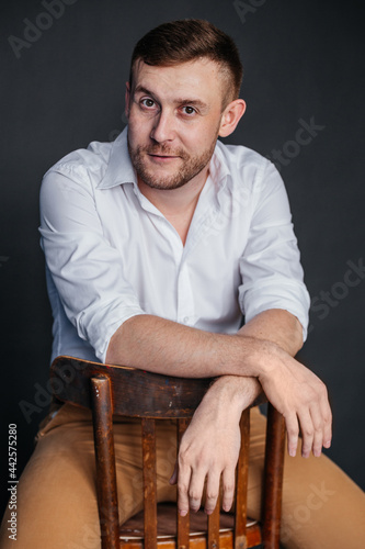 A man sits on a chair hanging his hands