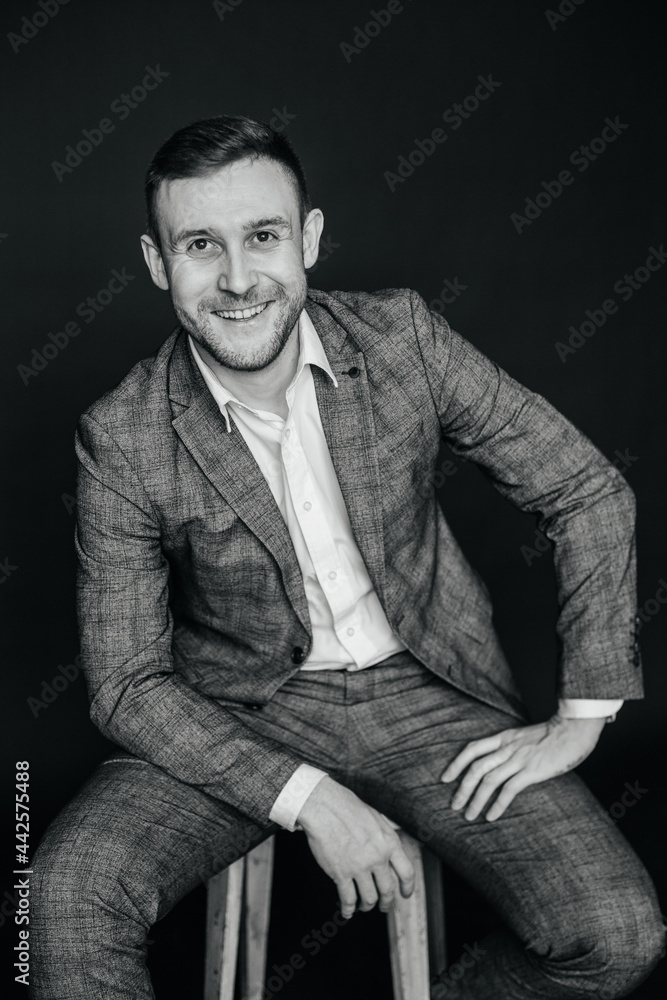Fototapeta premium Portrait of a man who sits on a chair and laughs, balck and white