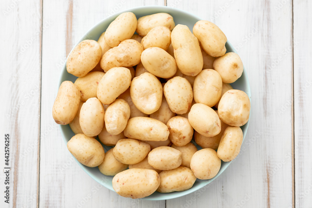 Young raw potatoes small on a plate on a white wooden background. Young raw potatoes small on a plate on a white wooden background.