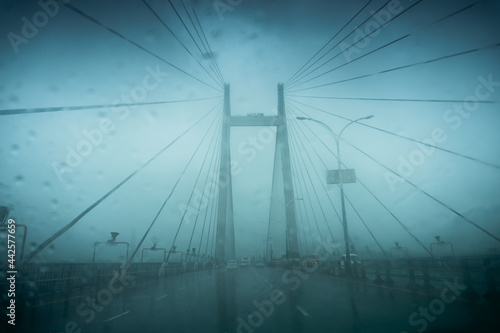 Vidyasagar Setu (Bridge) over river Ganges, known as 2nd Hooghly Bridge in Kolkata,West Bengal, India. Abstract image shot aginst glass with raindrops all over it, monsoon image of Kolkata. #442577659
