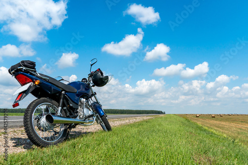 A motorcycle trip through the countryside in the summer. A blue motorcycle on a background of blue sky and white clouds.