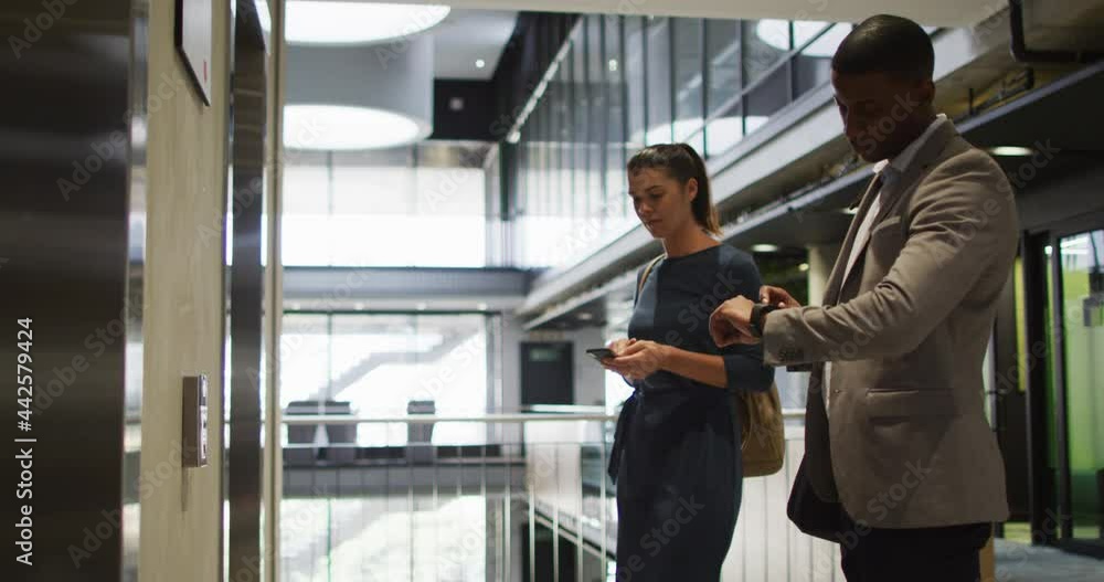 Diverse businessman and businesswoman waiting for lift and arriving in modern office Diverse businessman and businesswoman waiting for lift and arriving in modern office