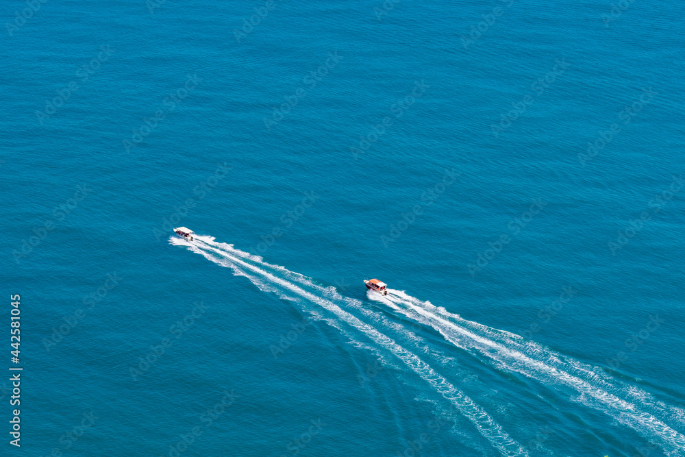 Naklejka premium Top view of two boats sailing at high speed. Aerial view of boats in motion on blue water.