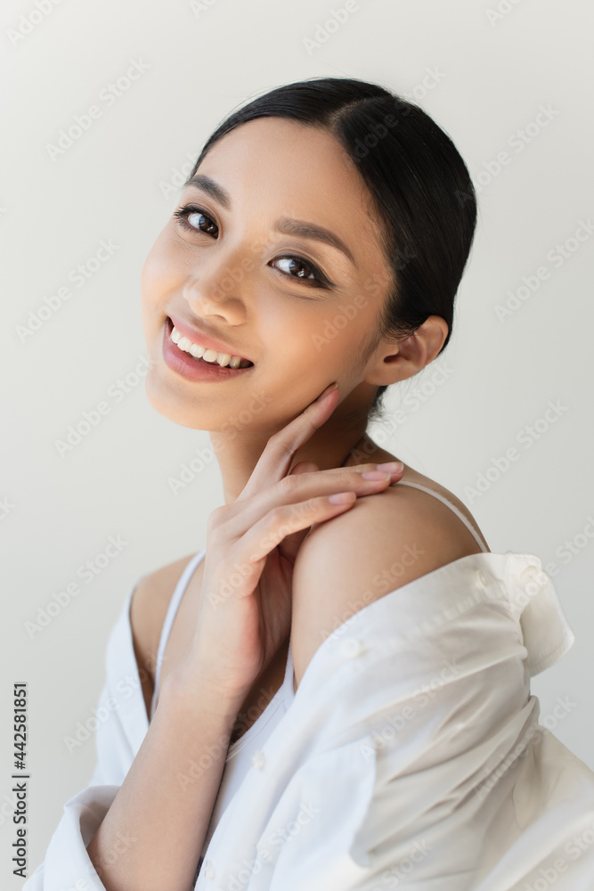 Japanese woman with finger near cheek smiling isolated on grey Japanese woman with finger near cheek smiling isolated on grey