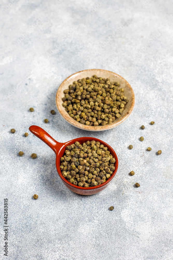 Green peppercorns in a small bowl and spoon. Green peppercorns in a small bowl and spoon.