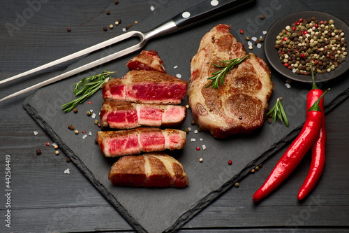 Grilled sliced roated beef steaks on stone serving cutting board
