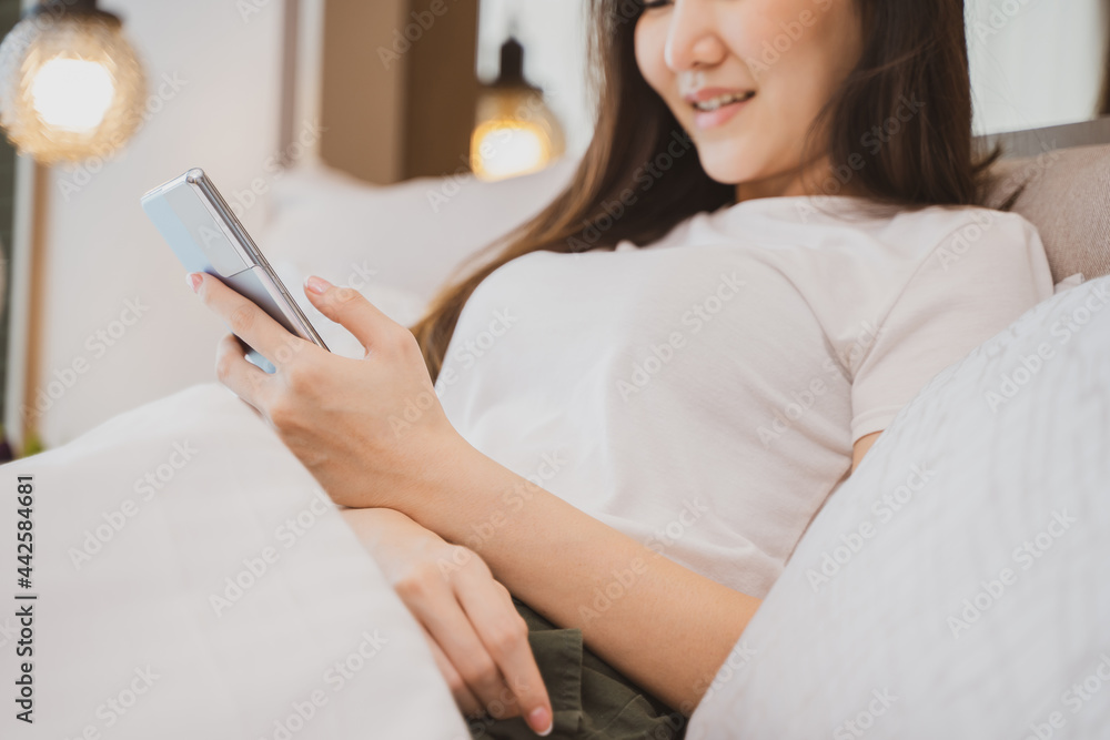 happy Young asian woman holding cellphone in bed technology lifestyle concept happy Young asian woman holding cellphone in bed technology lifestyle concept