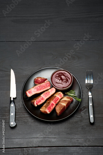 Grilled roated beef steaks on black ceramic plate photo