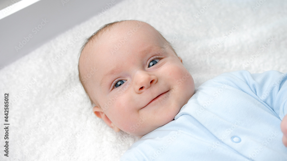 Portrait of happy smiling baby boy with blue eyes smiling on dressing table. Concept of hygiene, baby care and healthcare Portrait of happy smiling baby boy with blue eyes smiling on dressing table. Concept of hygiene, baby care and healthcare