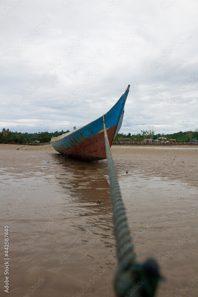 A fishing boat tied with a blue rope on the beach A fishing boat tied with a blue rope on the beach