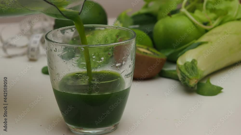 woman cuts green fruits and vegetables to blending spinach, cucumber, ice to make a healthy green smoothie. Woman pouring a green detox juice from blender to a glass woman cuts green fruits and vegetables to blending spinach, cucumber, ice to make a healthy green smoothie. Woman pouring a green detox juice from blender to a glass