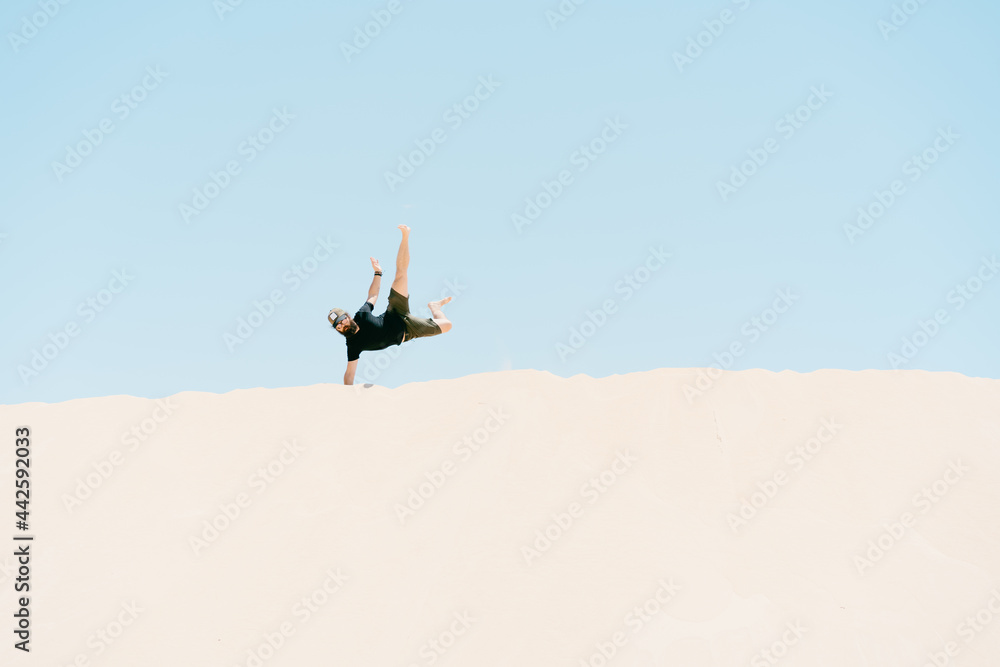Young man doing handstand in the sand dunes. concept of holidays and freedom Young man doing handstand in the sand dunes. concept of holidays and freedom