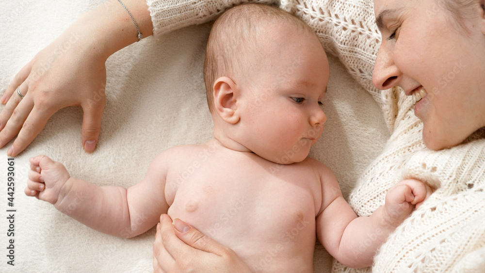 Portrait of little baby boy lying with mother on soft blanket in bed. Concept of parenting ,baby hygiene and child care Portrait of little baby boy lying with mother on soft blanket in bed. Concept of parenting ,baby hygiene and child care