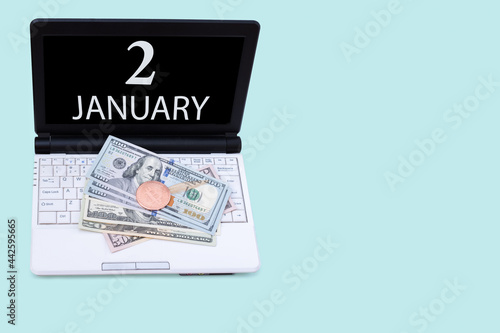 Laptop with the date of 2 january and cryptocurrency Bitcoin, dollars on a blue background. Buy or sell cryptocurrency. Stock market concept.
