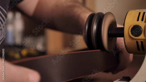 Wallpaper Mural The master sharpens the edges of the belt on a special machine. A leather craftsman makes a men's leather belt by hand in a small workshop. Family business with handmade Torontodigital.ca