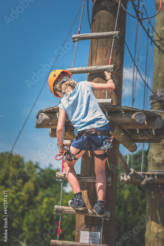 Fototapeta Naklejka Na Ścianę i Meble -  child having fun climbing up wooden ladder in rope climbing centre