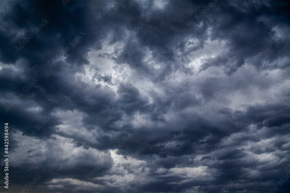 Stormy black clouds close the sky to the horizon. Dark thunderstorm clouds all over sky create an incredibly menacingly beautiful pattern.